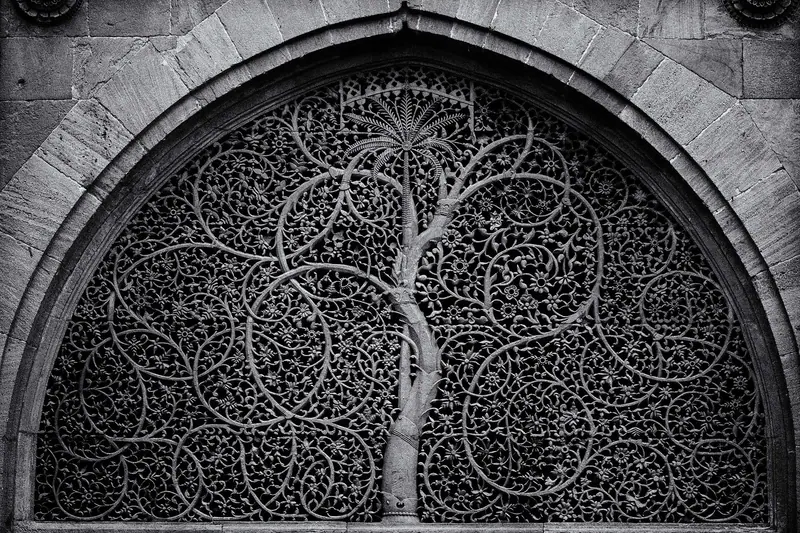 A carved stone lattice window showing an intertwined tree