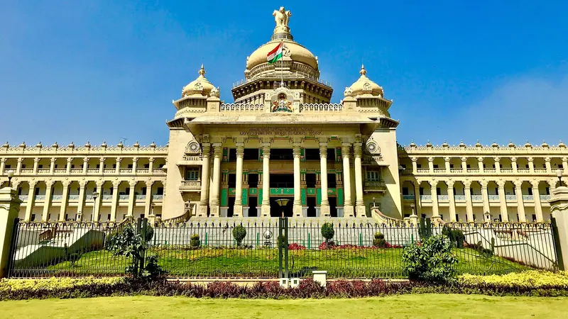 The granite Vidhana Soudha building with its domes under a blue sky, a garden in front