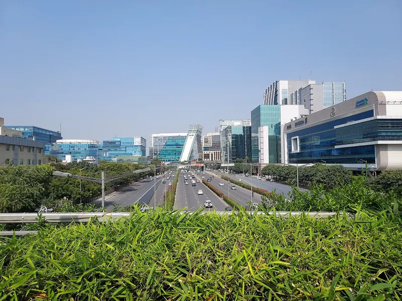 Glass office towers of Cyber City beyond a green highway median