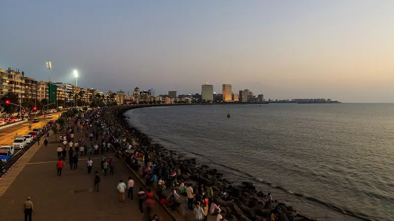 Crowds on the Marine Drive promenade at dusk, the bay curving away to the city